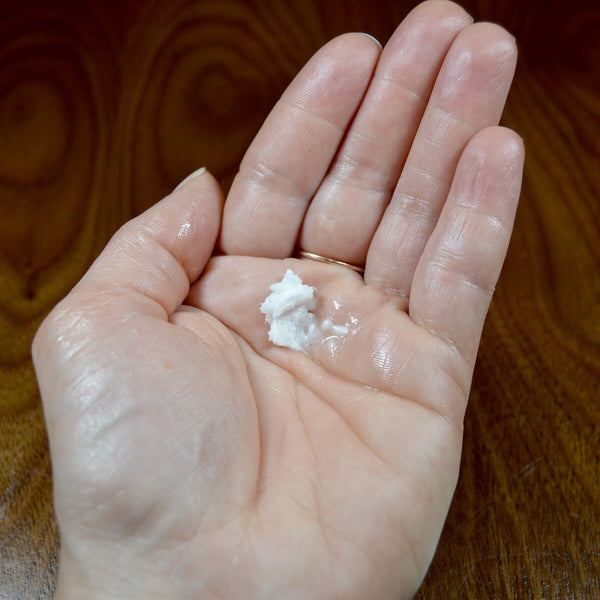 Hand with a pea-sized dab of body butter in the palm to demonstrate the amount needed for moisturizing both hands.